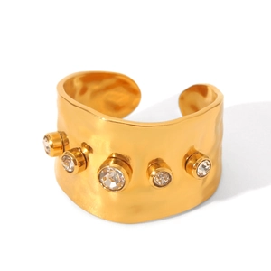 Dettaglio anello largo in acciaio placcato oro 18K con finitura martellata e 5 zirconi
