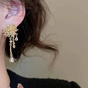 Macro shot of gold-plated tassel earrings with pearls and crystals on female model
