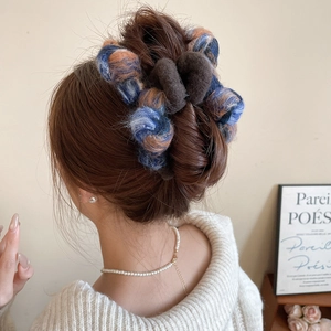 Close-up of a tricolor knitted bow hair claw clip worn in a messy bun hairstyle