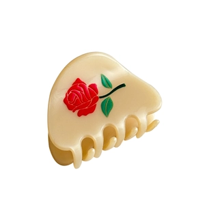 Beige acetate hair claw clip with red rose and green leaf pattern on white background