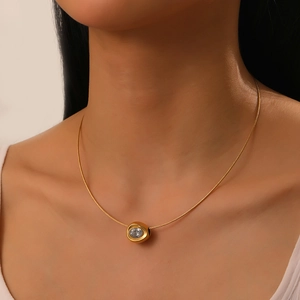 Close-up of gold-plated necklace with oval clear crystal pendant on female neck