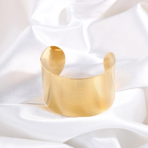 Close-up of wide golden stainless steel cuff bracelet with horizontal ribbed texture