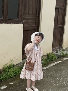 Detail of a brown woven crossbody bag styled with a floral dress and straw hat