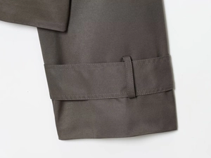 Detail view of deep olive trench coat cuff with button strap and twill fabric texture