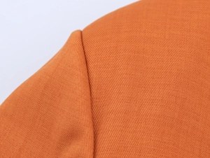 Macro shot of the orange twill fabric texture and stitching detail on the blazer shoulder