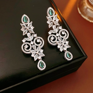 Detailed macro view of teardrop emerald earrings on luxury black leather jewelry box
