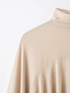 Detail shot of apricot turtleneck top showing fine fabric texture and premium stitching