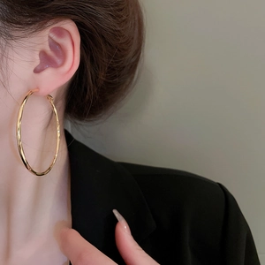 Polished gold hollow hoop earrings on model showing large minimalist circle design