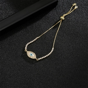 Detail of adjustable golden evil eye bracelet with white zircon inlay on black background