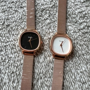Detail of square quartz watches with rose gold mesh bands in black and white dials