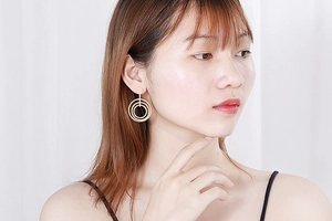 Detail of triple-layered concentric gold circle drop earrings worn by a model