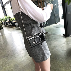 Sac bandoulière chic en forme d'appareil photo avec chaîne argentée porté par un mannequin