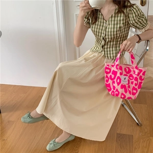 Pink leopard print canvas tote bag styled with a green plaid top and white midi skirt