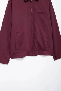 Detailed view of wine red zip-up jacket featuring lapel collar and chest pocket