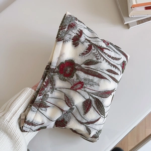 Detailed close-up of delicate floral embroidery on cream fabric pouch for women