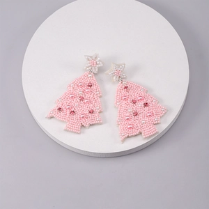 Detailed close-up of handmade pink beaded Christmas tree earrings on white display