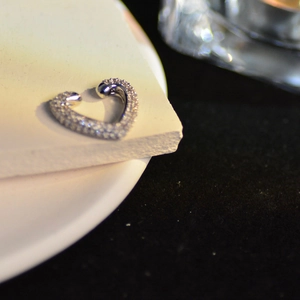 Macro detail of heart-shaped silver ear cuff with micro-paved sparkling zircon stones