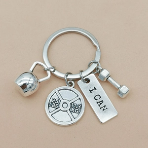 Detail shot of silver fitness keychain with kettlebell, dumbbell and engraved plate charms