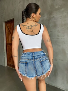 Detail von High-Waist Denim-Shorts mit ausgefranstem Saum und weißem Crop-Top
