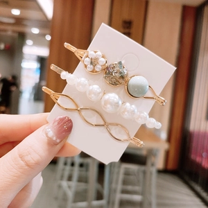 Détail de trois barrettes dorées avec perles et strass bleus sur support blanc