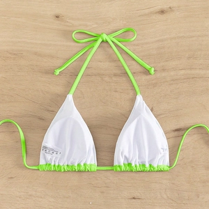 Flat lay detail of a white triangle bikini top with neon green ties and a fabric care label