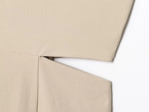 Close-up of split hem design and fine woven fabric texture on khaki pleated dress