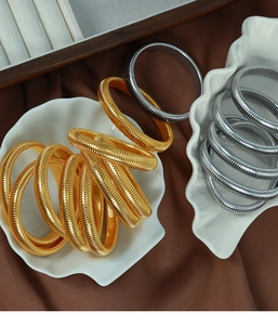 Close-up of gold and silver textured stretch metal bracelets in a shell display tray