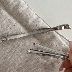 Detail of silver metal hair clips showing the duckbill structure and engraved text