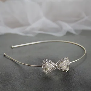 Dettaglio del cerchietto dorato con fiocco di perle bianche e strass su sfondo scuro