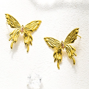 Close-up of gold butterfly stud earrings featuring a central pink cubic zirconia inlay