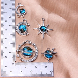 Detail of blue enamel moon and star charms with rhinestones on satin with a ruler