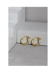 Macro shot of polished gold hoop earrings on minimalist stone, showing high-gloss texture