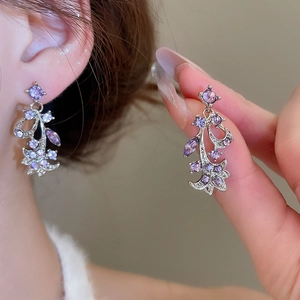 Close-up detail of silver floral earrings featuring purple marquise cut crystals