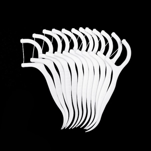 Macro shot of white plastic dental floss picks with bow design on black background