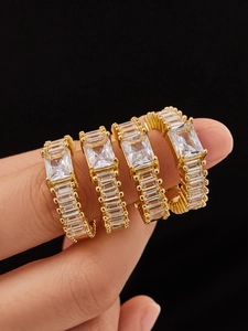 Macro shot of 4-piece gold-plated zircon rings set with baguette-cut stones on fingers