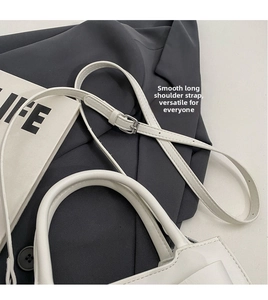 Detail of white matte leather handbag with adjustable shoulder strap and silver buckle