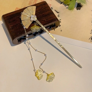 Détail d'une épingle à cheveux éventail dorée avec glands en perles et feuilles de ginkgo