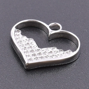 Macro shot of silver heart pendant with textured inlay on minimalist stainless steel necklace