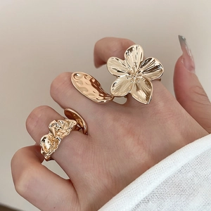 Close-up of a hand wearing gold flower and irregular textured rings on fingers