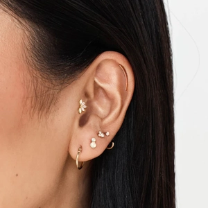 Close-up of gold dragonfly and bee stud earrings set with stones on a female ear
