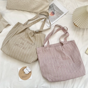 Close-up of striped canvas tote bags with smile embroidery in soft lifestyle setting