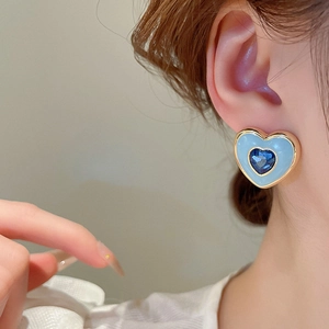 Close-up of blue heart earring with enamel inlay and rhinestone on model ear