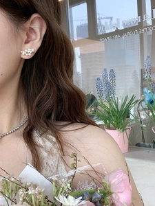 Close-up of model wearing pearl flower earrings with white petals and gold plating