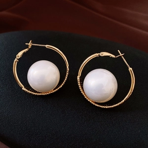 Detailed close-up of gold geometric hoop earrings with large round white pearls