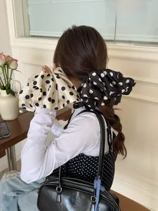 Close-up of oversized satin polka dot scrunchie with elegant pearl charm detail