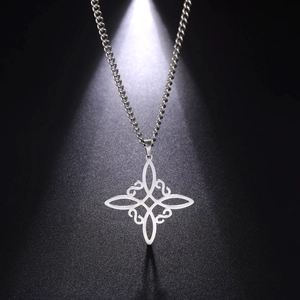 Dramatic close-up of a silver Celtic knot pendant necklace on a black textured surface