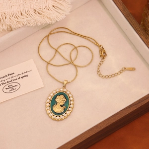 Macro detail of a vintage French-style gold portrait pendant with pearls and green base