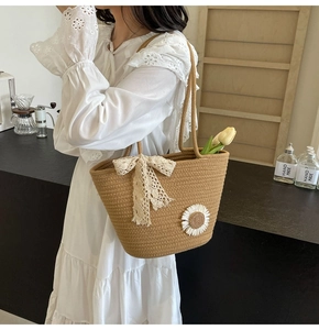 Detail of hand-woven tote bag featuring sunflower applique and lace bow on strap