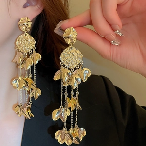 Long gold tassel earrings with hammered metal petals worn by a model to show scale