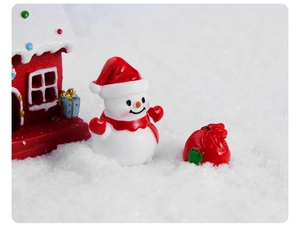 Set in miniatura con pupazzo di neve, casetta rossa e sacchetto regalo sulla neve